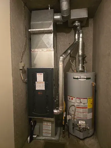 Furnace, water heater, and ductwork in a narrow utility closet.