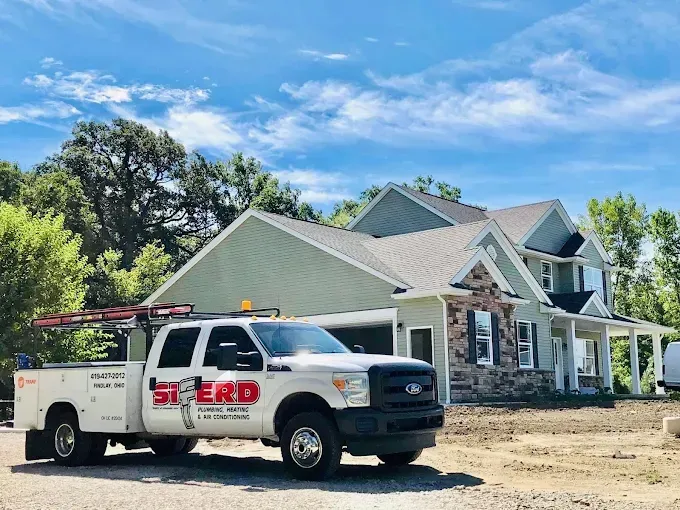 White utility truck parked in front of a newly built house under a blue sky