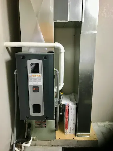 Electrical panel and wiring mounted beside a metal duct in an industrial utility room.