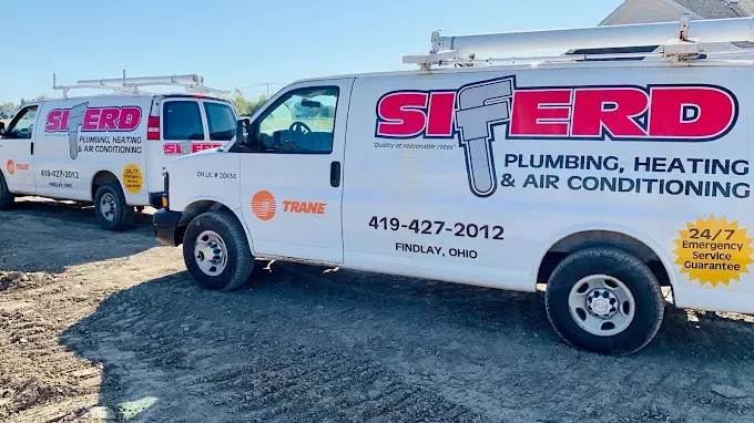 Two SERVD plumbing and air conditioning service vans parked on a gravel lot.