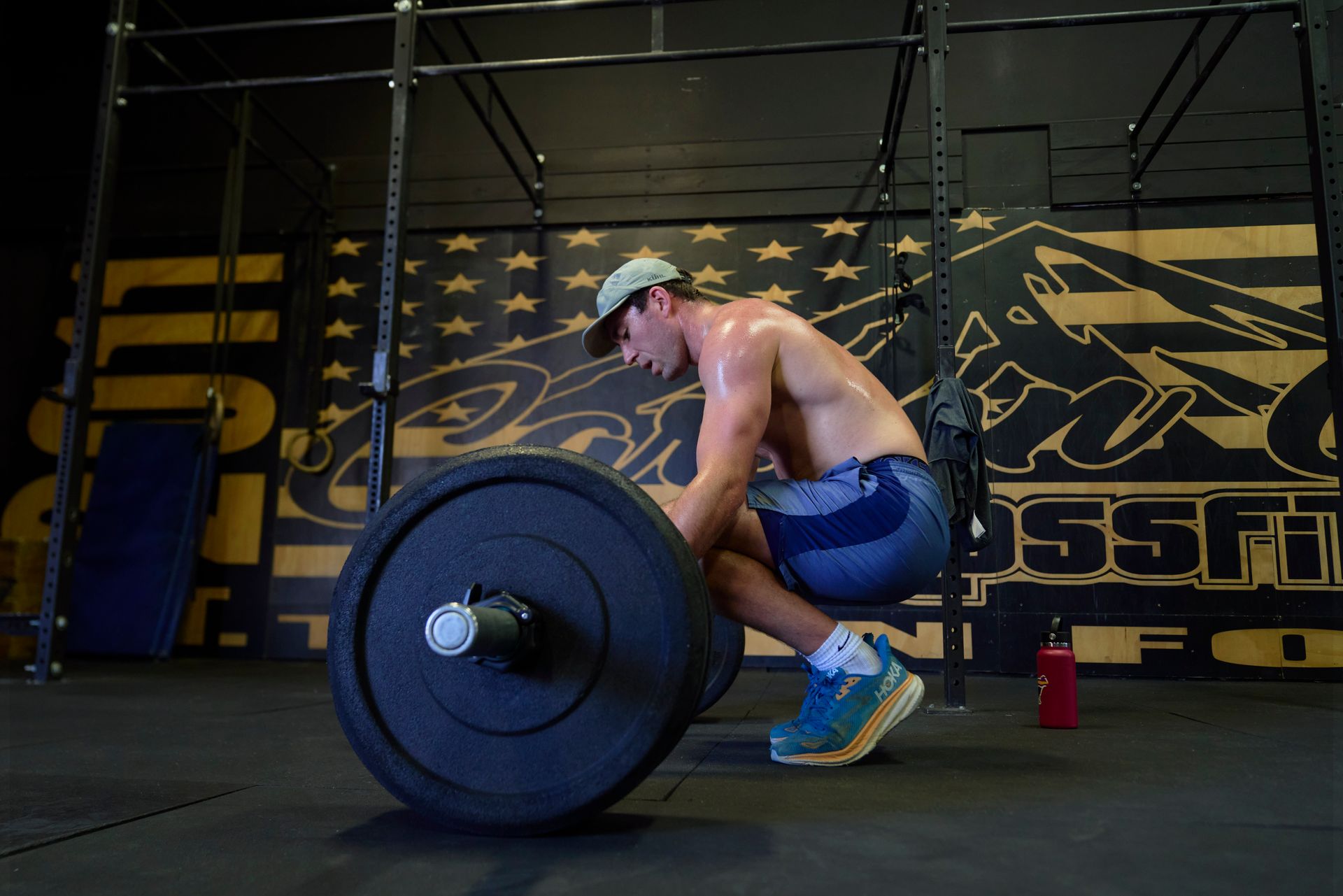 Athlete lifting a barbell in Carson City CrossFit, a gym in Carson City, Nevada, crouched on the floor with chalk and a water bottle nearby.
