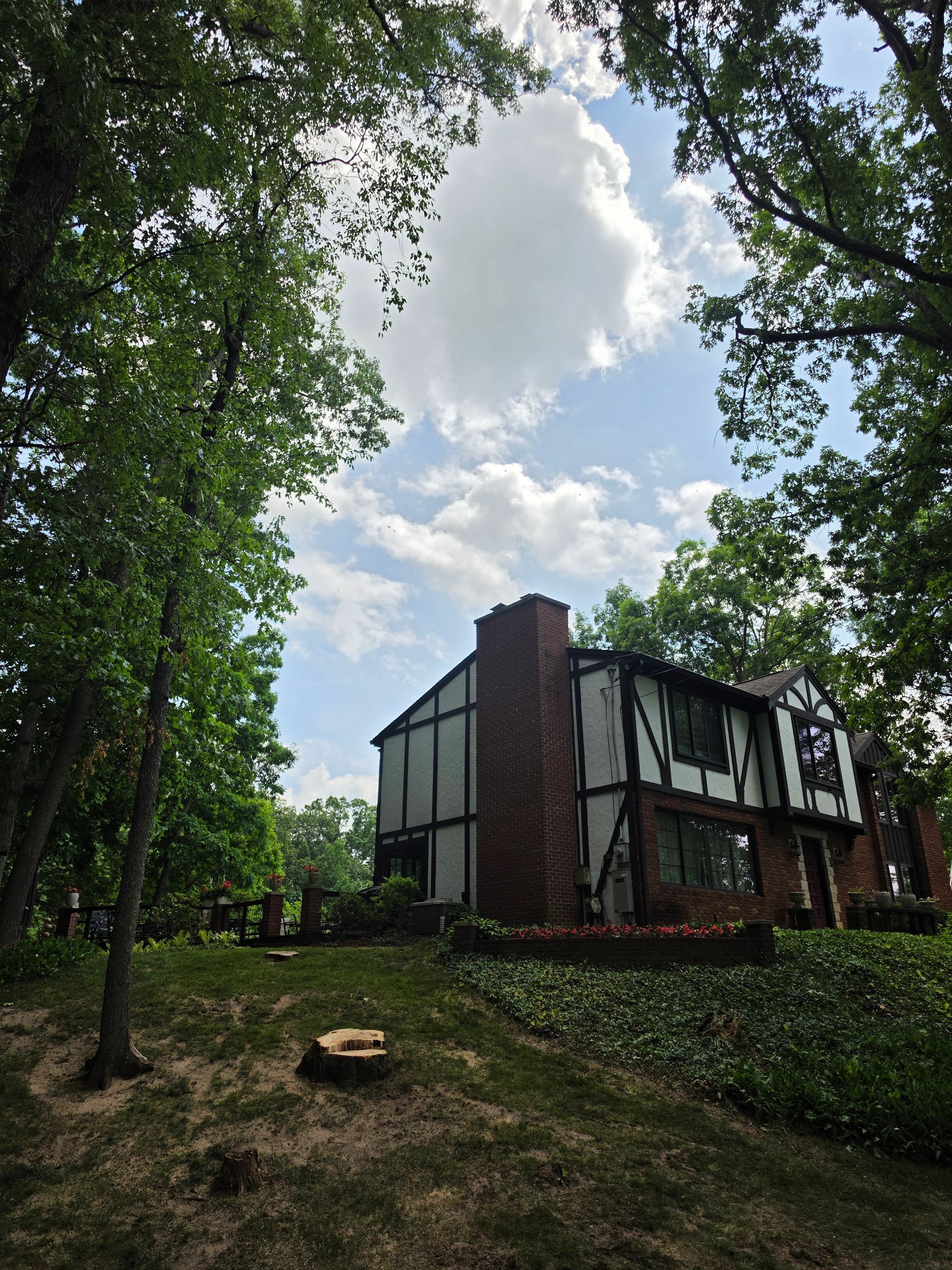 Modern house among trees on a wooded hillside under a partly cloudy sky