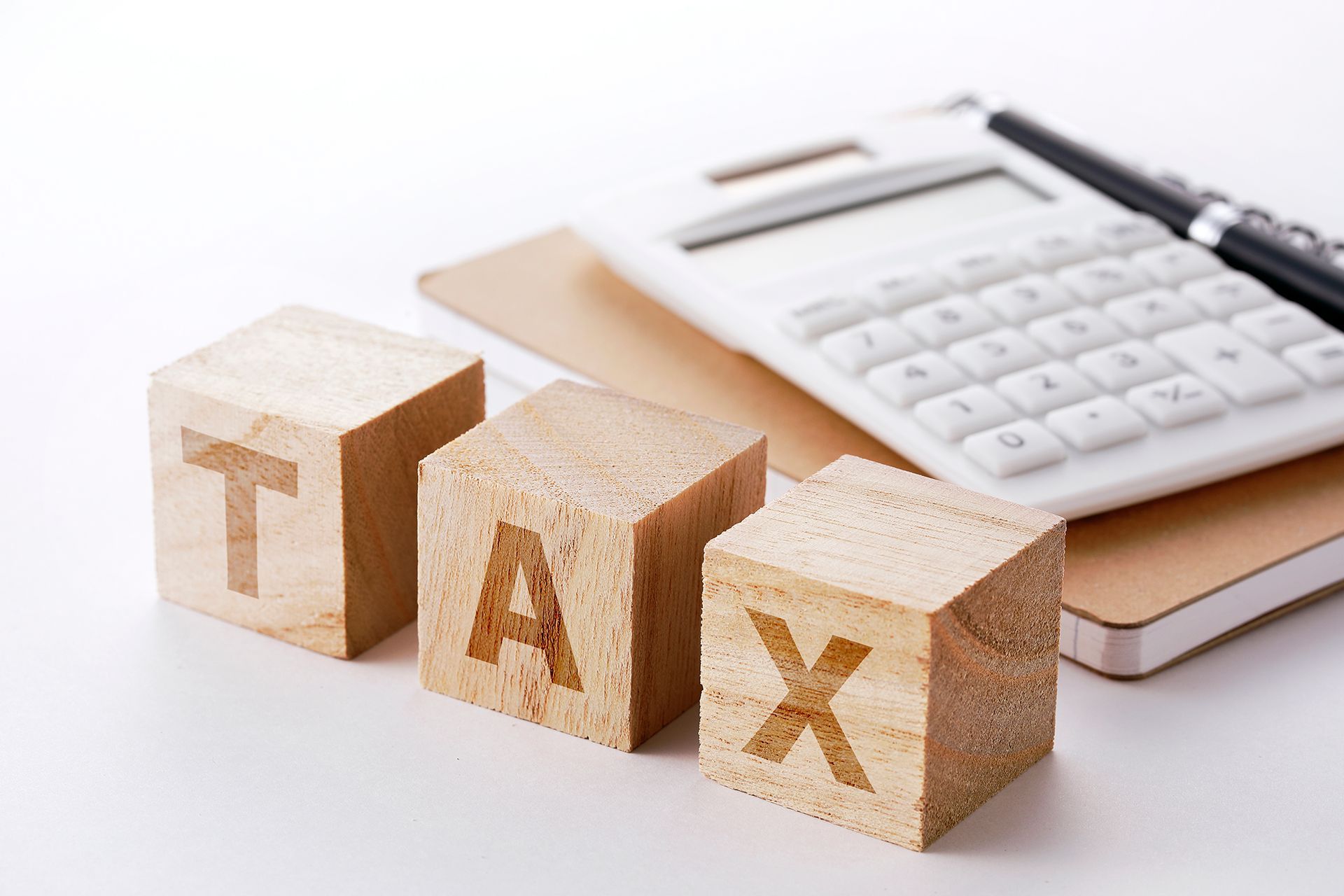 The word tax is written on wooden blocks next to a calculator.