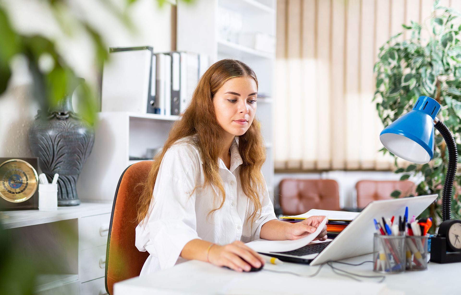 A woman is sitting at a desk using a laptop computer.