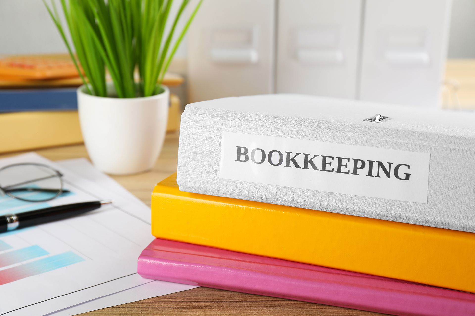 A stack of bookkeeping binders sitting on top of each other on a desk.