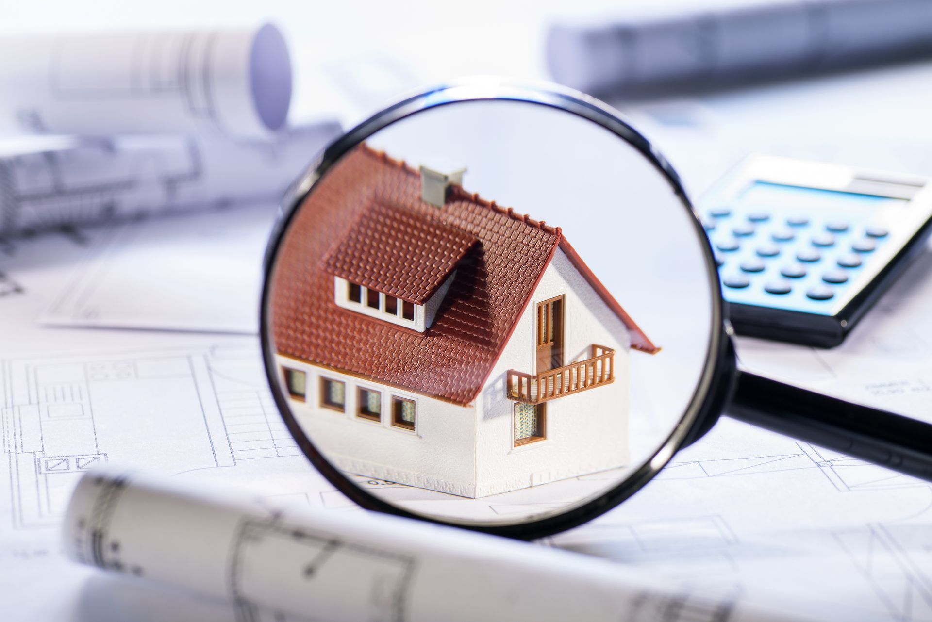 A magnifying glass is looking at a model house.