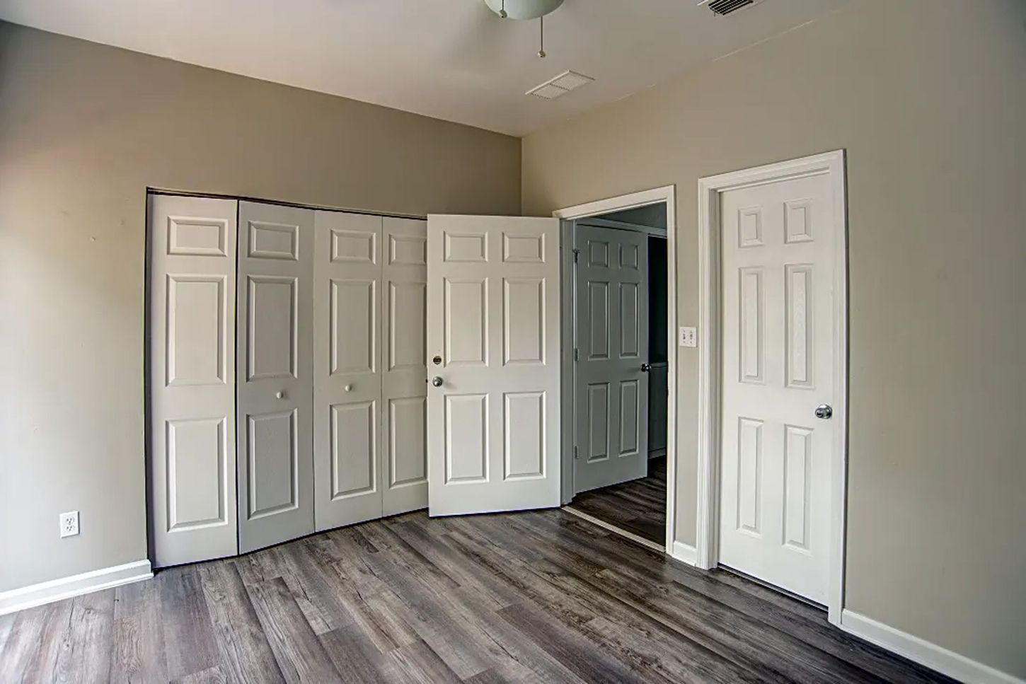 A bedroom with a lot of doors and a ceiling fan.