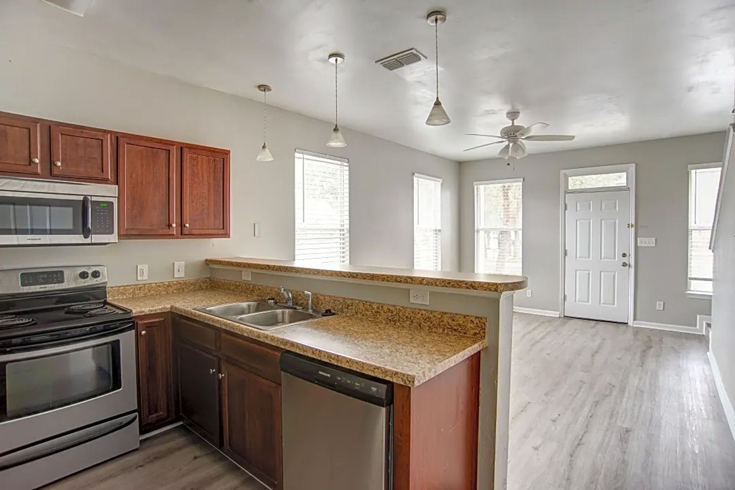 A kitchen with a stove , sink , dishwasher and microwave.