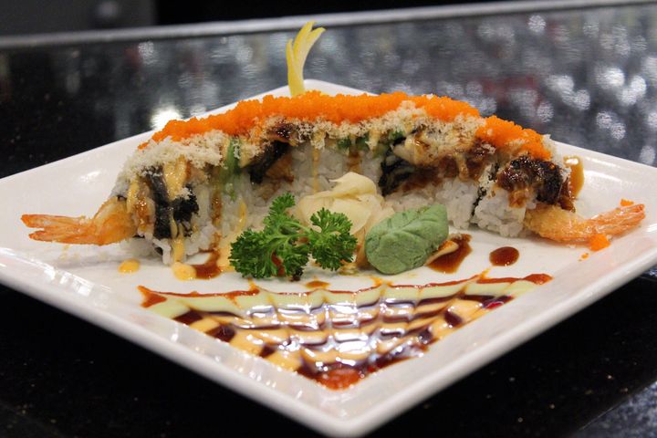A white plate topped with sushi and sauce on a table. A white plate topped with sushi and sauce on a table.