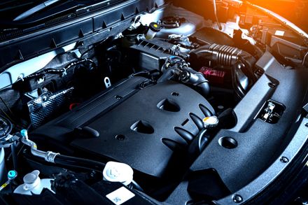 Un primo piano del motore di un'auto con il cofano aperto.