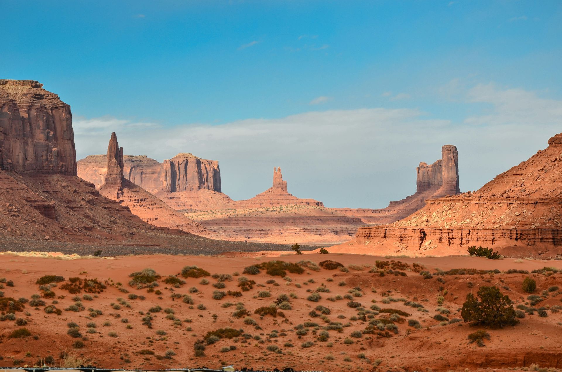 Red desert valley with sandstone buttes and mesas under a clear blue sky