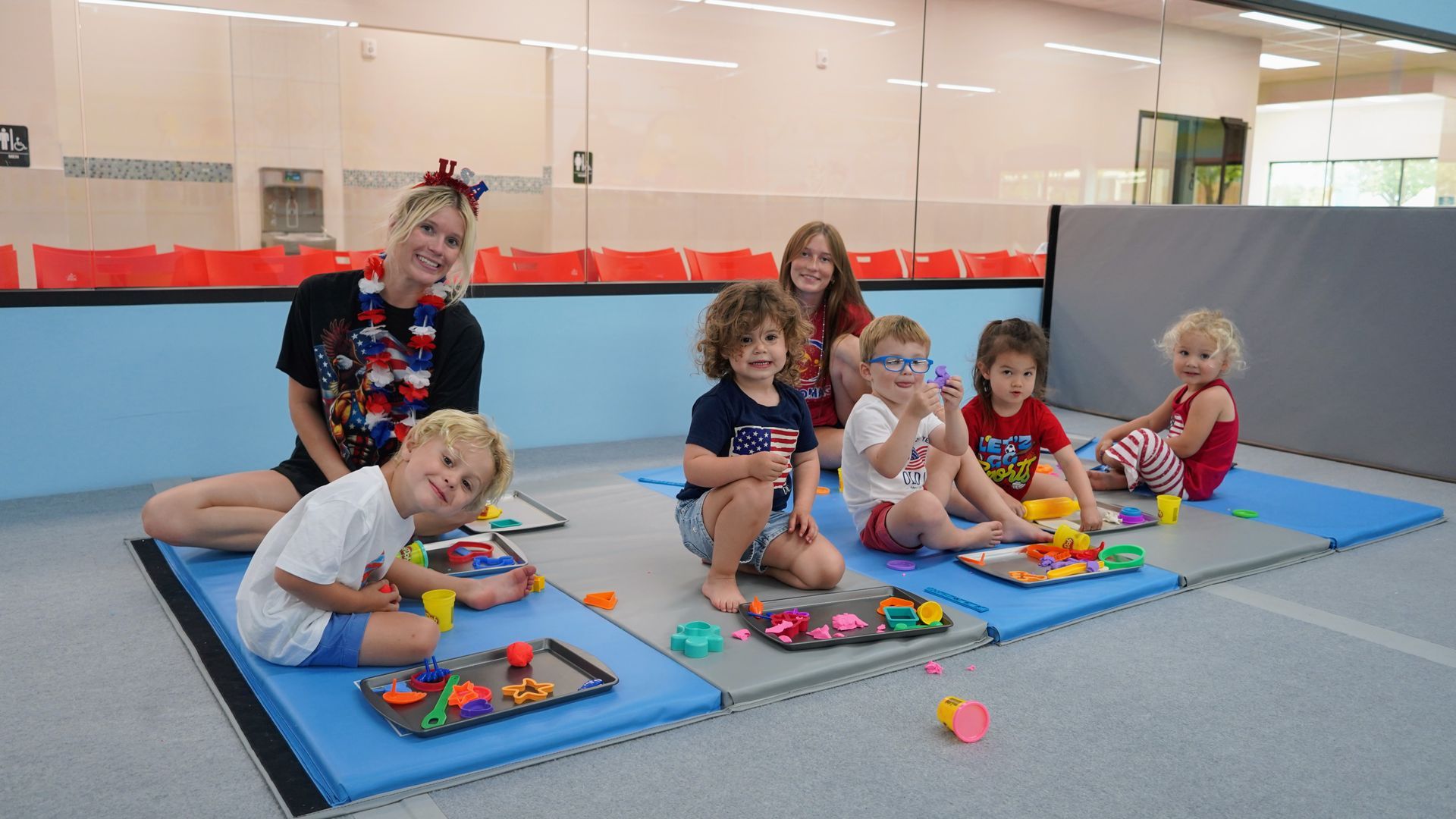 Children playing with colorful toys on mats in an indoor play area