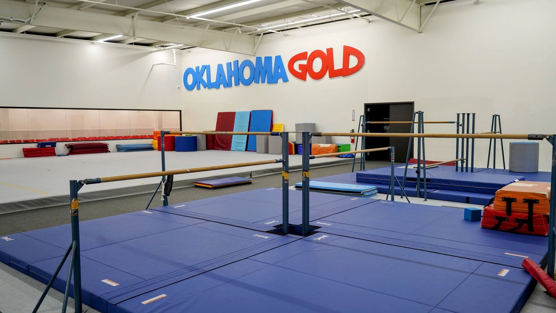 Boxing ring with blue mats and ropes in a gym labeled “Oklahoma Gold”