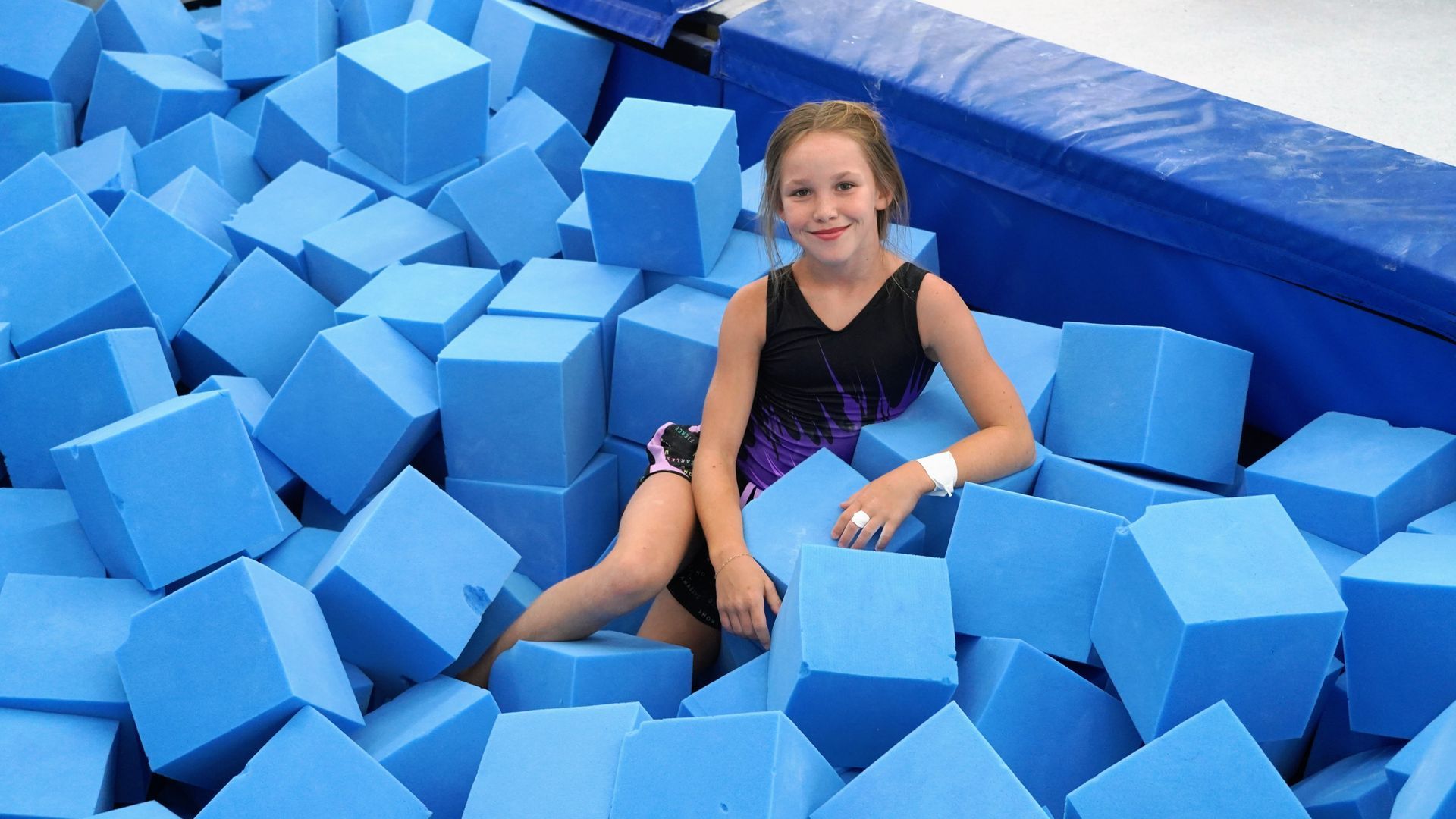 Girl smiling in a blue foam pit with scattered blue blocks around her