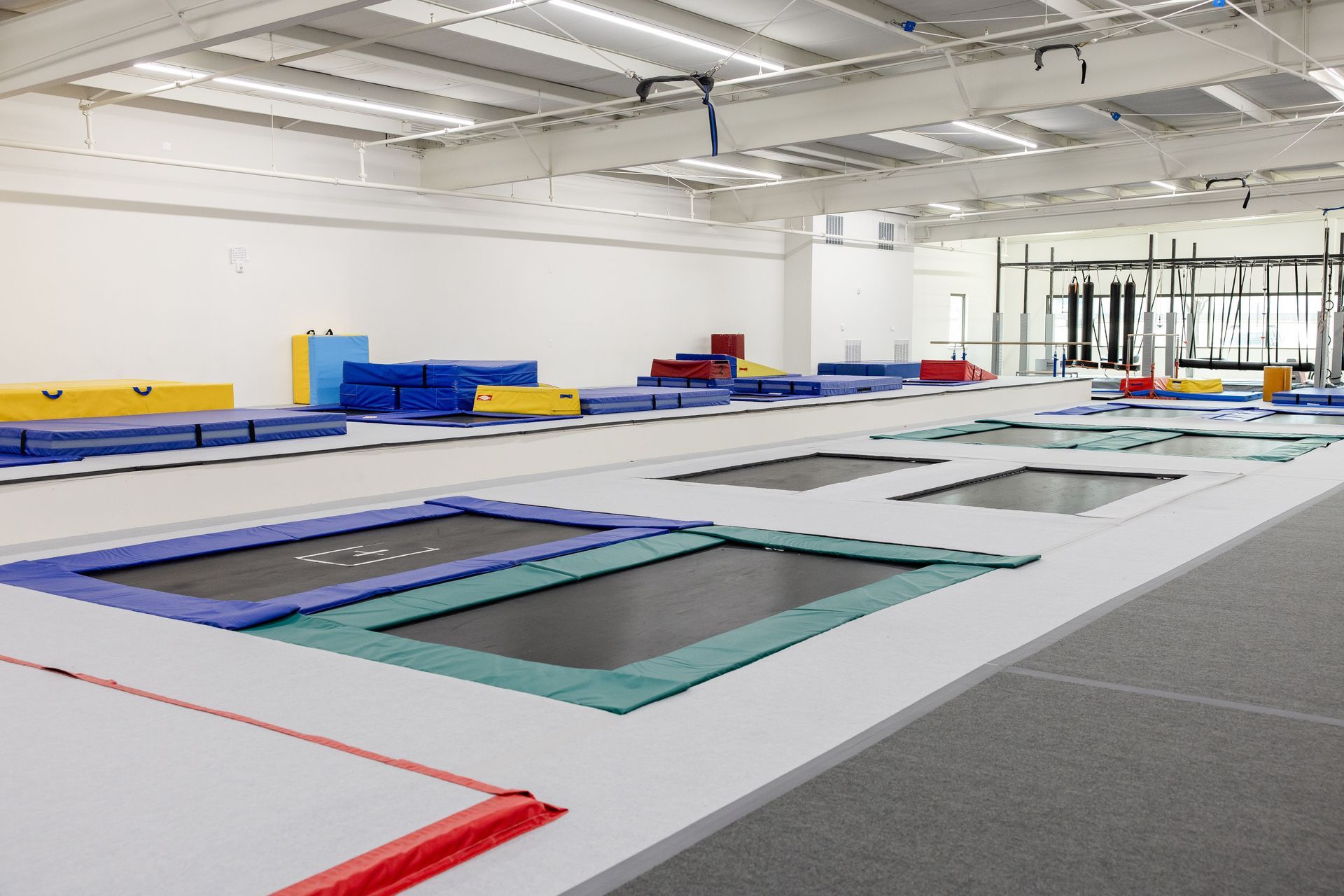 Indoor trampoline park with colorful trampolines and foam pits in a bright white room