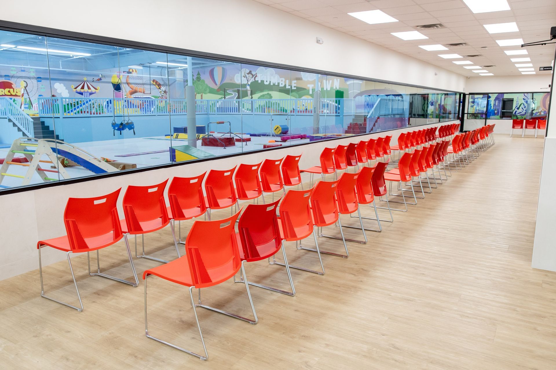 Bright viewing area with rows of red chairs and wall murals behind them