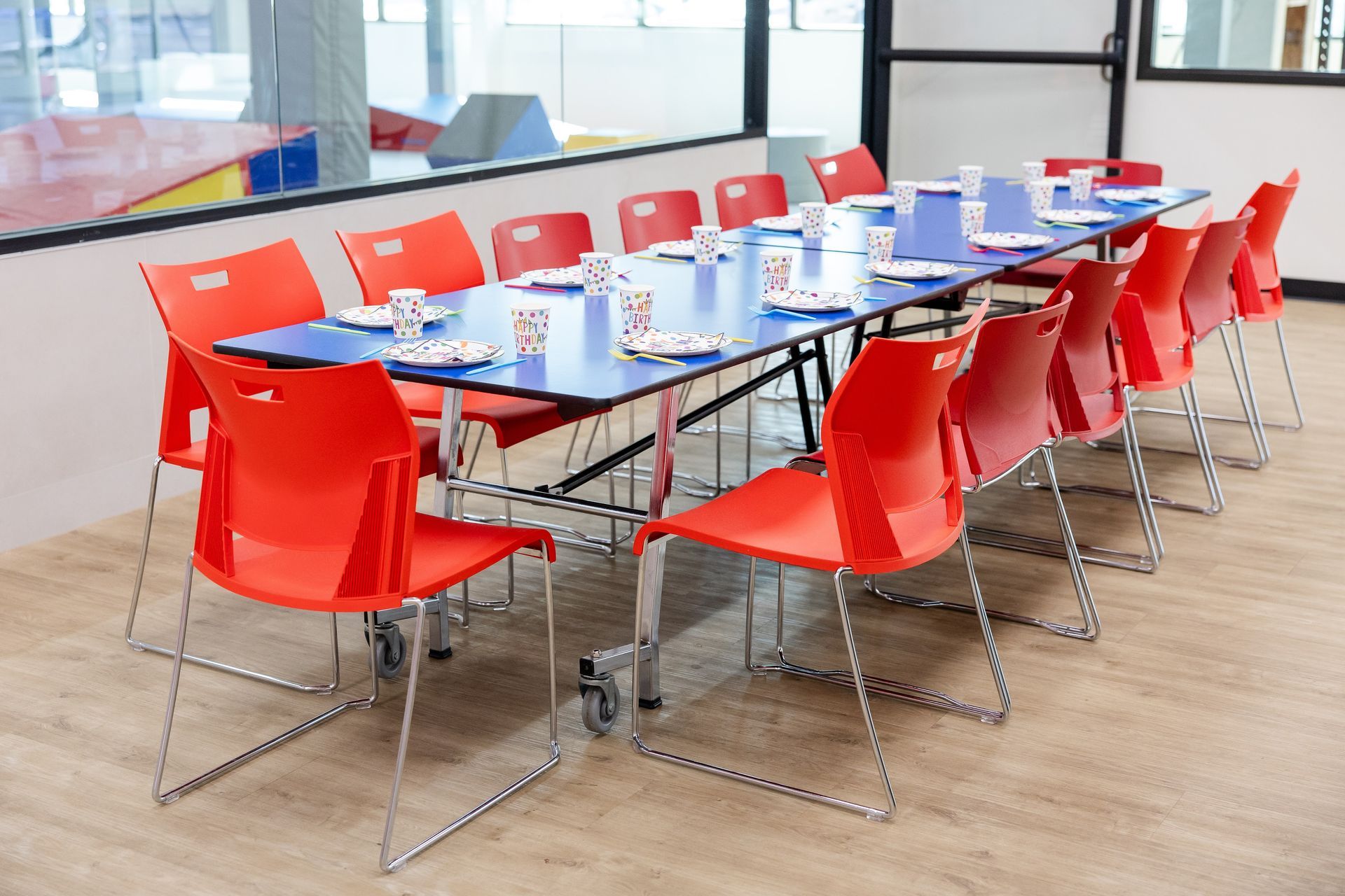 Birthday serving room with red chairs around a long table set with birthday decor