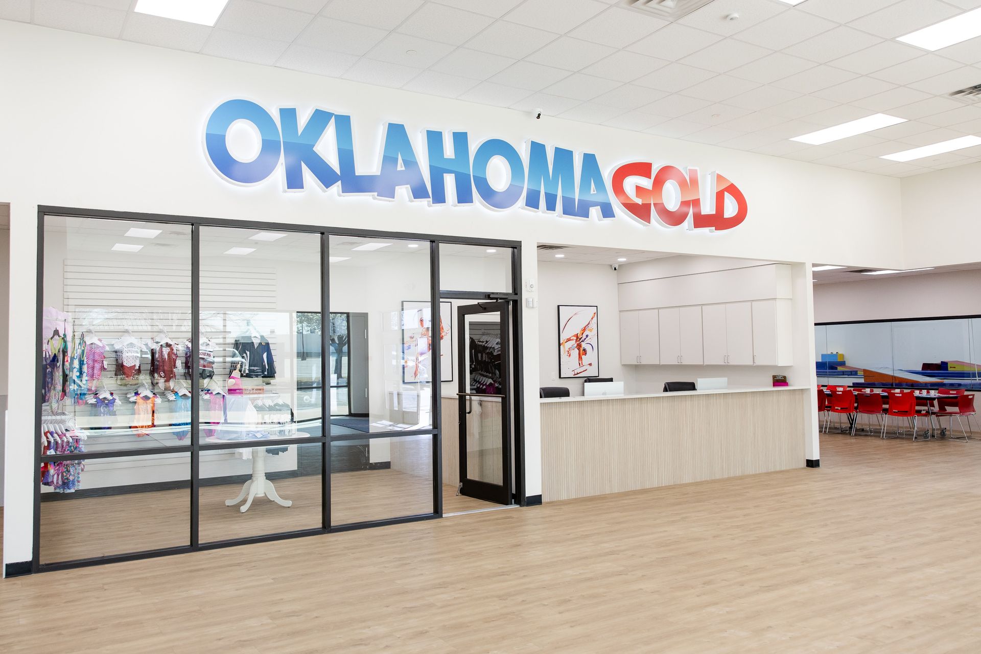 Oklahoma Gold storefront with glass doors, white counter, and blue-red sign in a bright mall-like interior