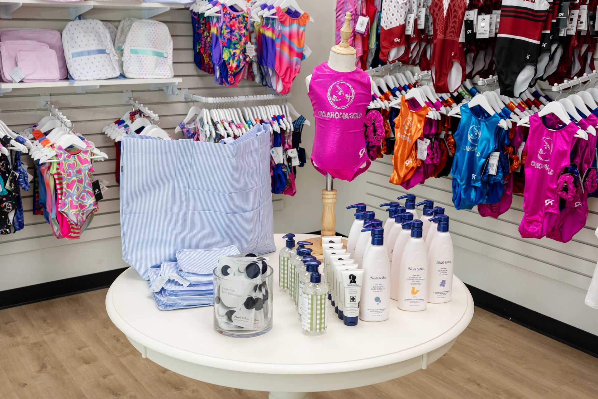Round display table with colorful pet clothes, towels, and grooming products in a store aisle