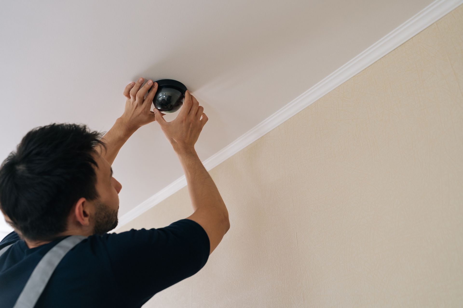 Technician installing a dome camera on a ceiling as part of residential security systems