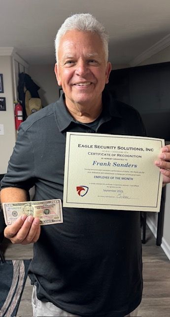 Man smiling, holding certificate and cash, indoors.