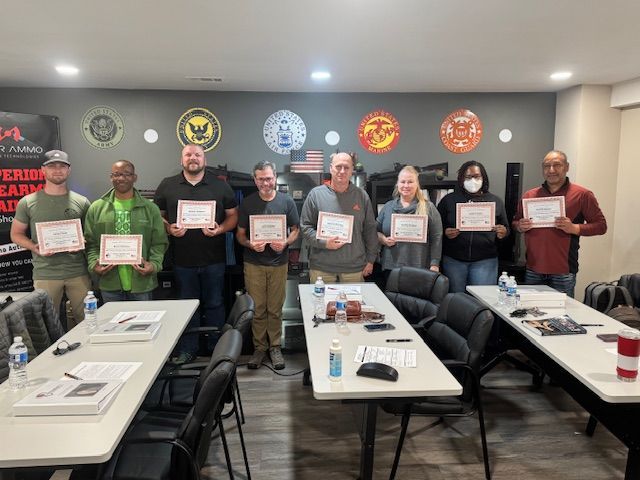 Group of people holding certificates, posing at a firearm training class.