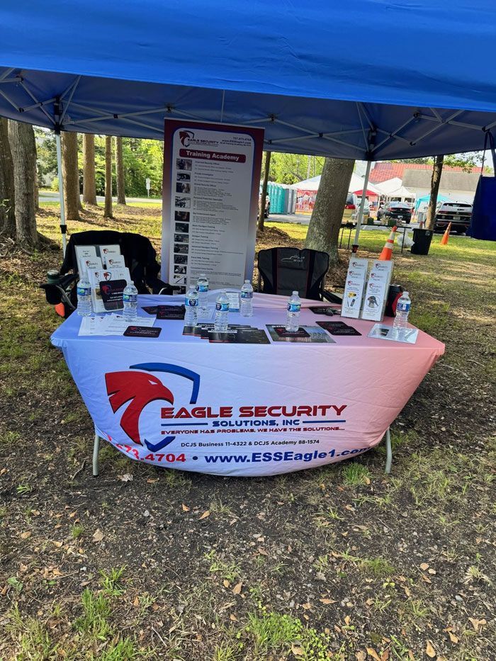 Booth for Eagle Security Solutions with products on a table under a blue canopy.