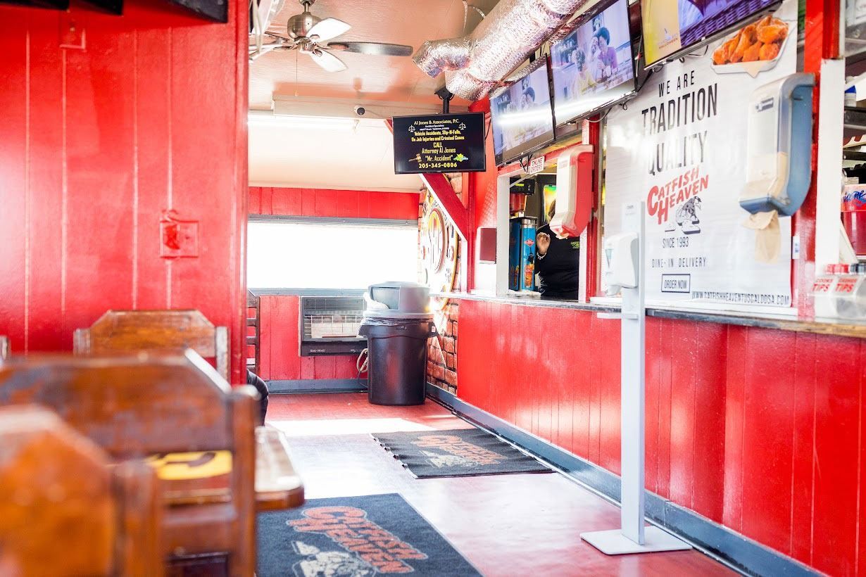 The inside of a restaurant with red walls and a counter.