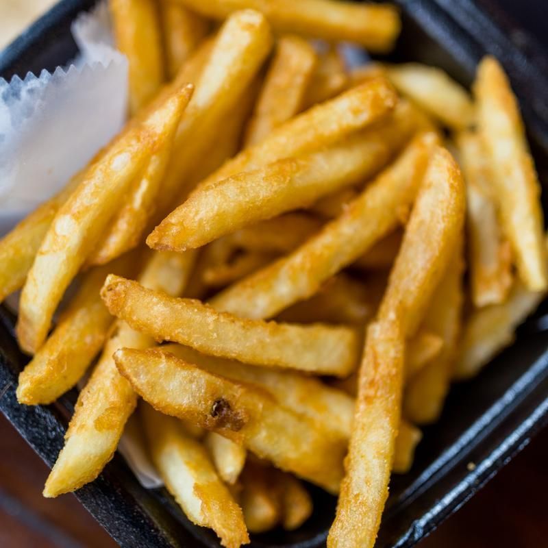 A close up of french fries in a black container