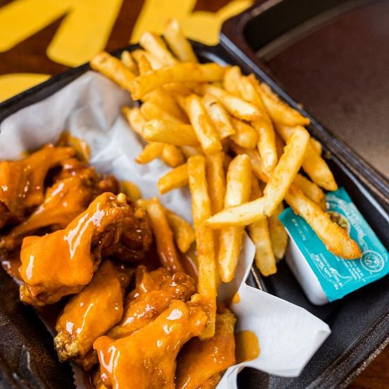 A tray of chicken wings and french fries with dipping sauce