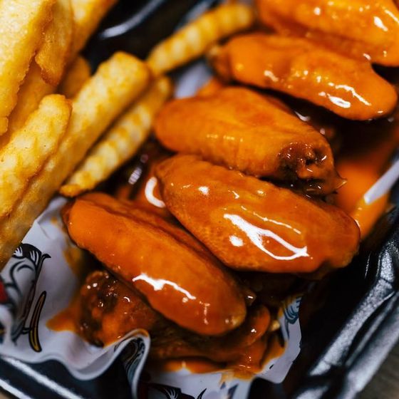 A basket of buffalo wings and french fries on a table
