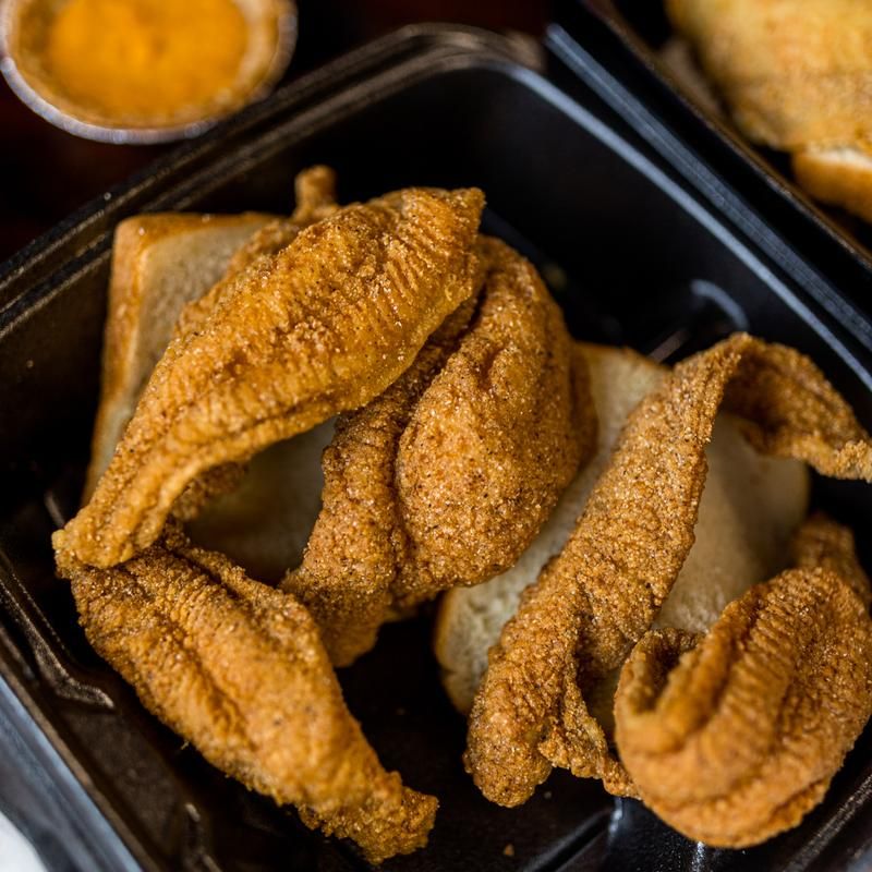 A plastic container filled with fried fish and bread.