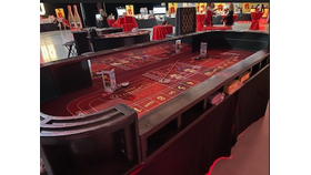 Casino gaming table with red felt and chips in a dimly lit arcade or gaming area