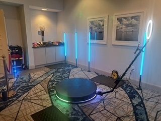Modern living room with blue LED light bars, a glowing circular platform, and framed wall art.