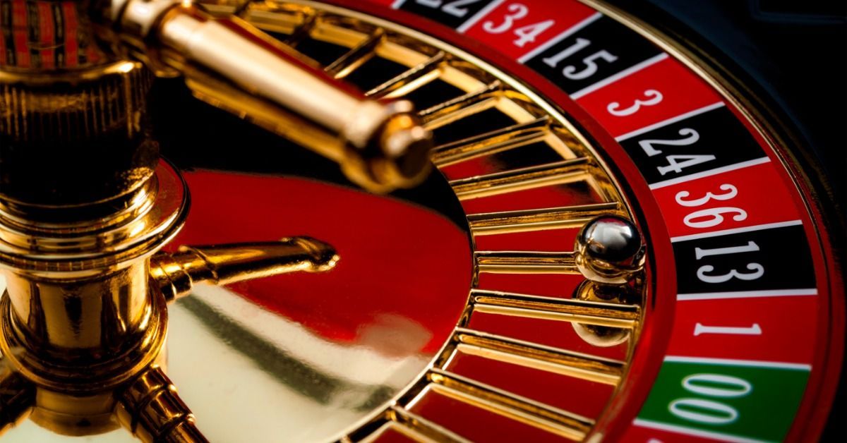 A shiny roulette ball rests in the black 13 slot in a close-up view of a red and black roulette wheel.