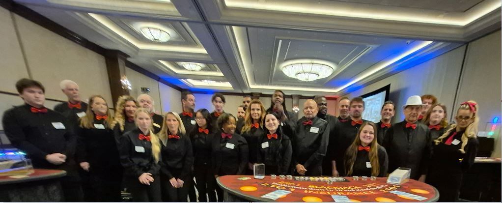 Group of people posing indoors behind a table with orange banners in a conference room