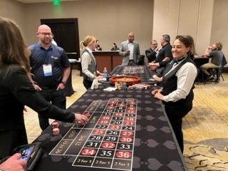 A group of people are playing roulette at a table in a room.