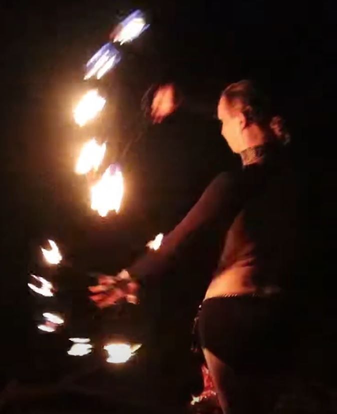 A woman is juggling fire in the dark