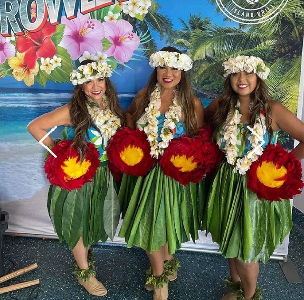 Three women in hawaiian costumes are posing for a picture
