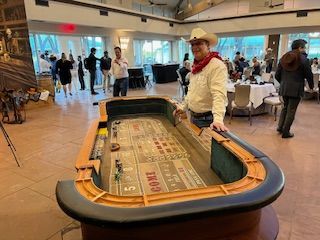 A man dressed as a cowboy is standing next to a craps table.
