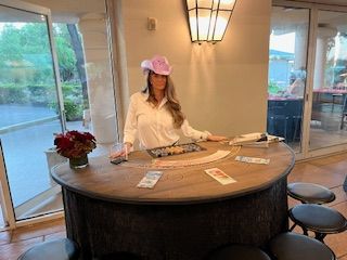 A woman in a pink hat is standing at a table with cards on it.