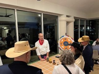 A group of people wearing cowboy hats are standing around a table.