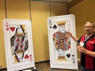 A man is standing in front of two giant playing cards.