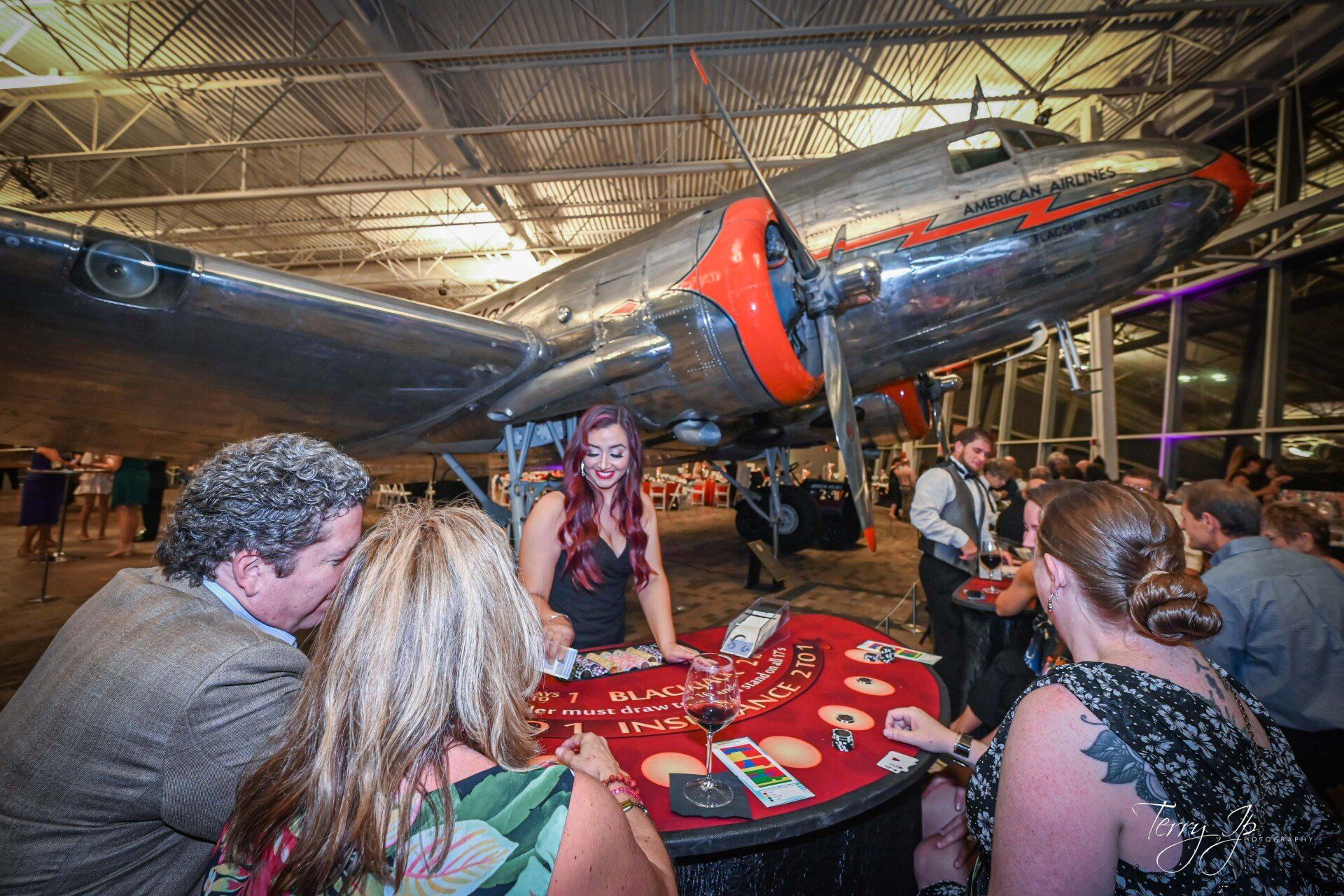 A group of people are playing a game of roulette in front of an airplane.