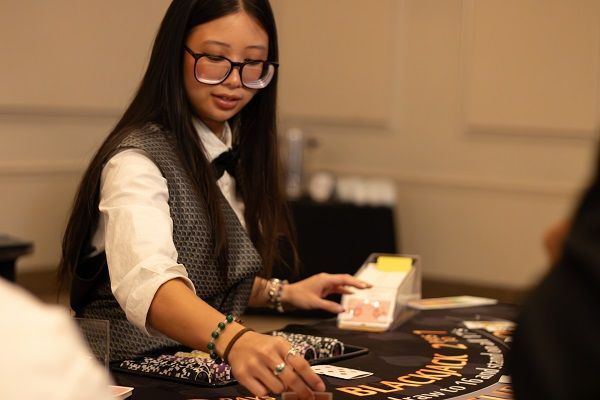 Woman blackjack dealer setting cards on table.