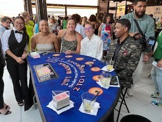 Group posing around a blue anniversary display table at an indoor event