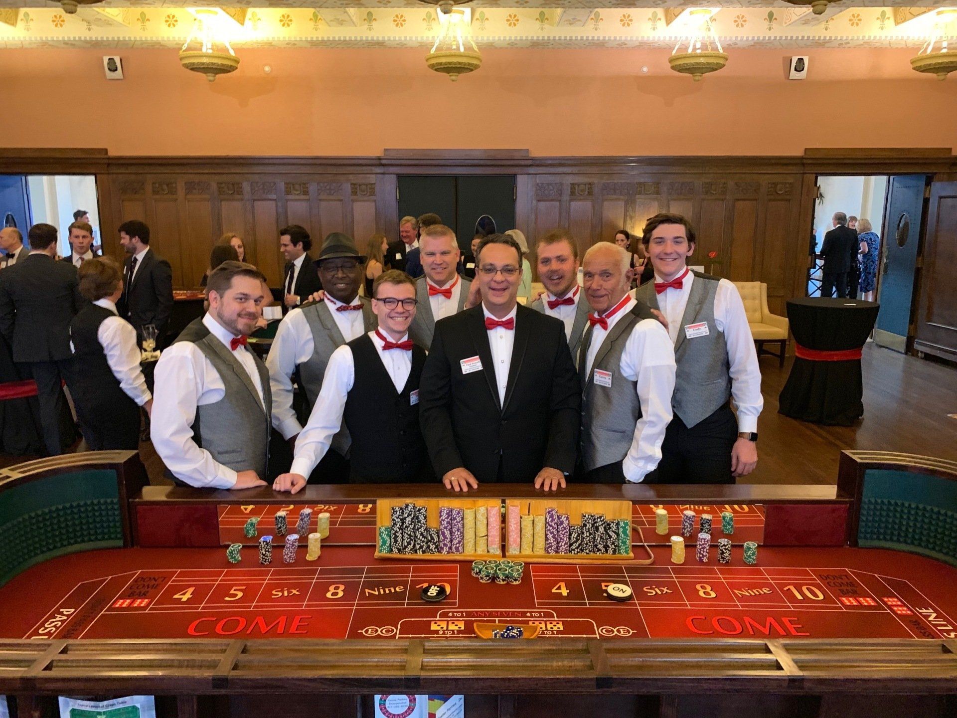 A group of men are posing for a picture in front of a casino table.