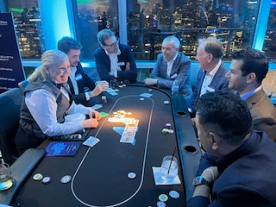 A group of people are sitting around a poker table.
