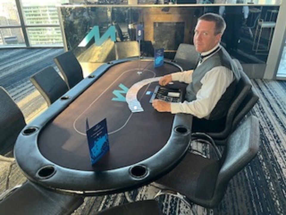 A man is sitting at a poker table with the letter m on it