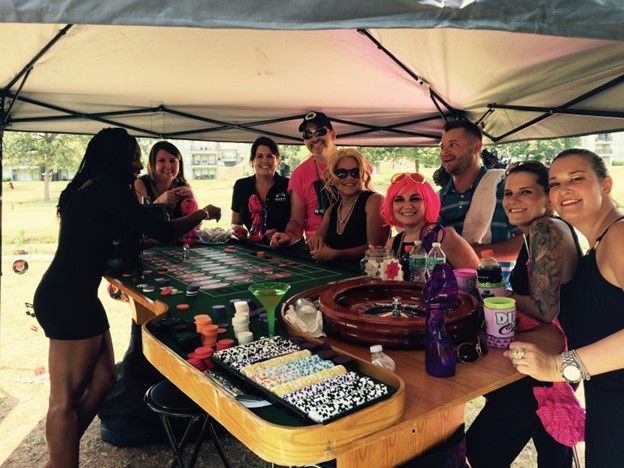 A group of people are sitting around a table with a roulette wheel.